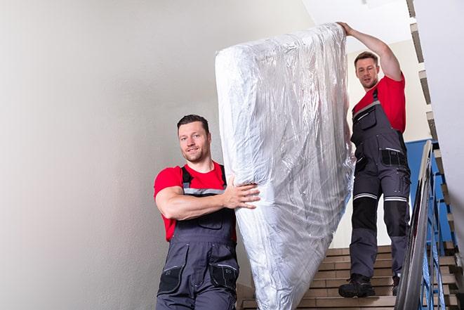 heavy lifting as box spring is transported out of a building in Garrison